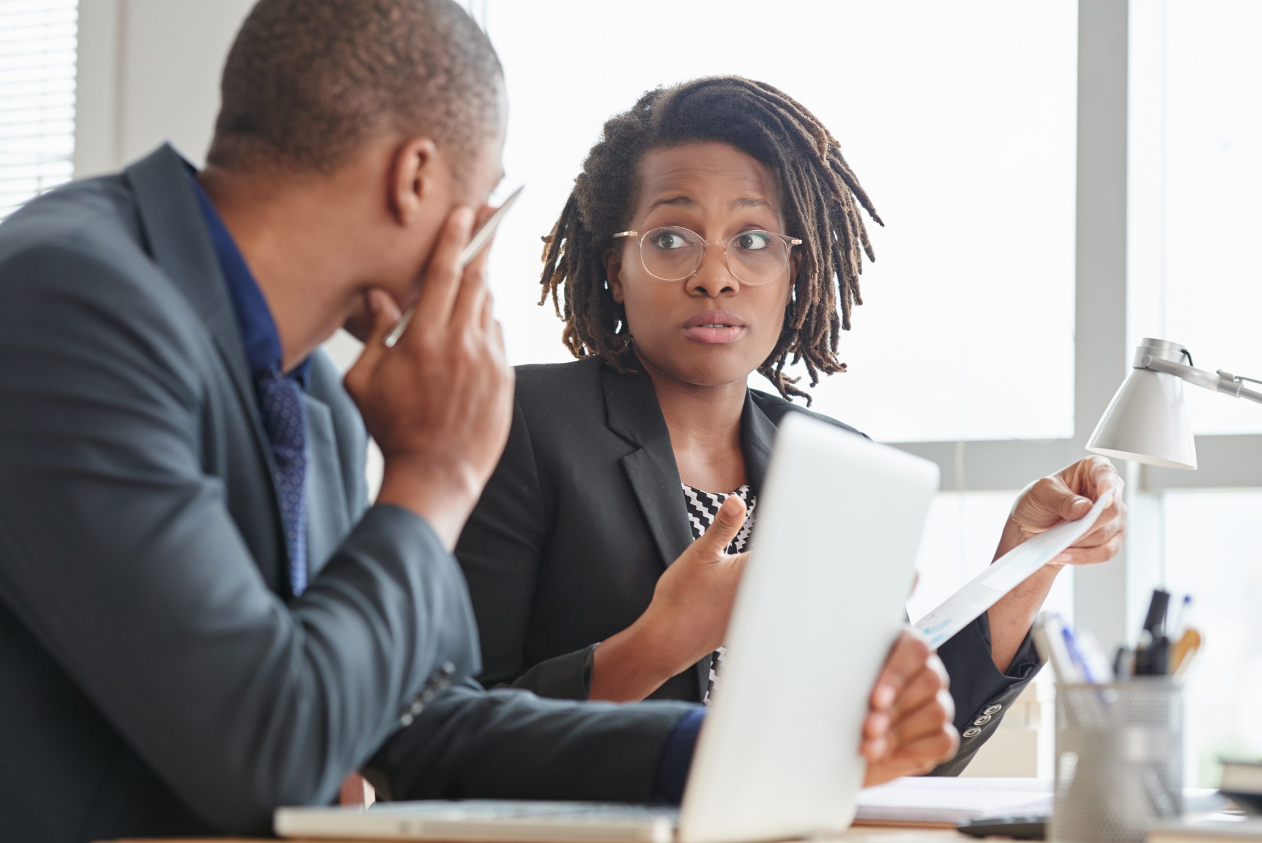Surprised business lady in glasses talking to male coworker