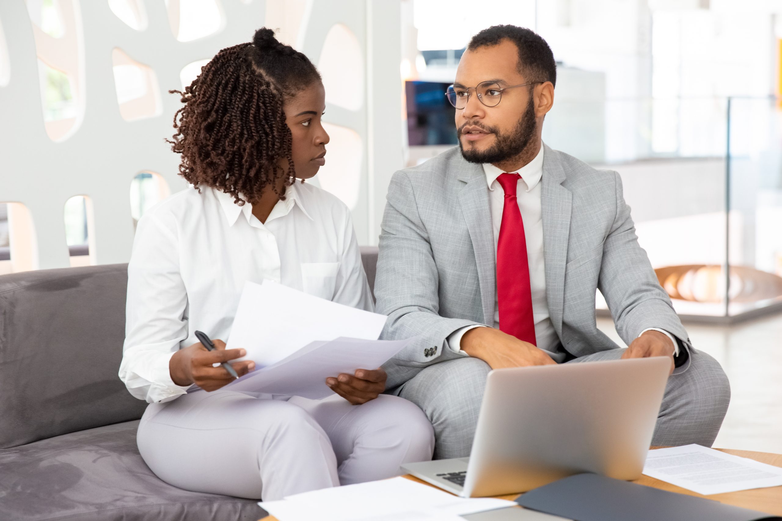 Confident young business people talking during meeting. Handsome young businessman talking with partner while sitting on sofa. Business meeting concept